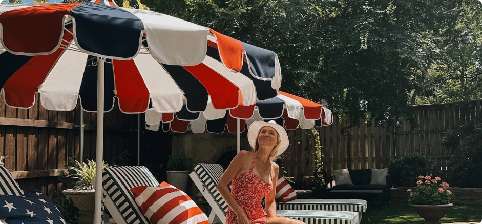 Patriotic outdoor retreat featuring the limited-edition Red, White, and Blue Tri-Color Pagoda Cut patio umbrella with Sunbrella fabric. This stylish backyard setting includes classic striped lounge chairs and bold Americana decor, creating an elegant yet festive summer ambiance.