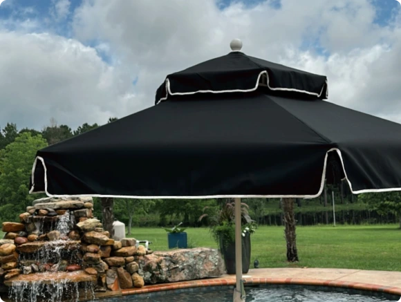 Luxurious poolside setup featuring the Terrace Series patio umbrella in all-black Sunbrella fabric with a double-tiered pagoda design and white trim. This elegant and sophisticated outdoor shade enhances any high-end patio, resort, or backyard retreat with timeless style and durability.