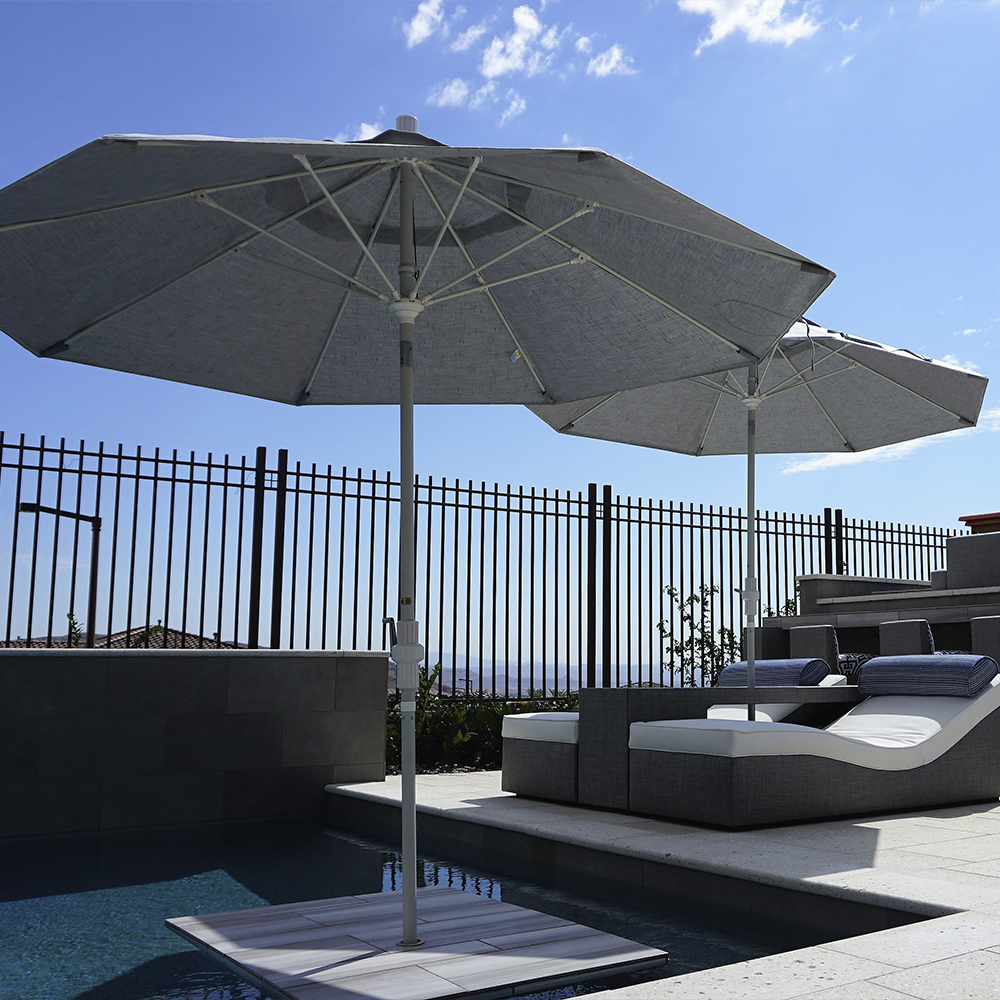 Image of the Sun Master Series Residential Patio Umbrella by California Umbrella, showcased in a vibrant backyard setting. This umbrella combines timeless elegance with modern technology, featuring a durable aluminum center pole and flexible fiberglass ribs for superior wind resistance. The revolutionary collar tilt mechanism allows for precise shade control, while the smooth crank lift ensures easy operation. Designed to withstand diverse weather conditions, the Sun Master Series provides lasting comfort and reliable shade, redefining outdoor relaxation with its seamless blend of classic and current features.